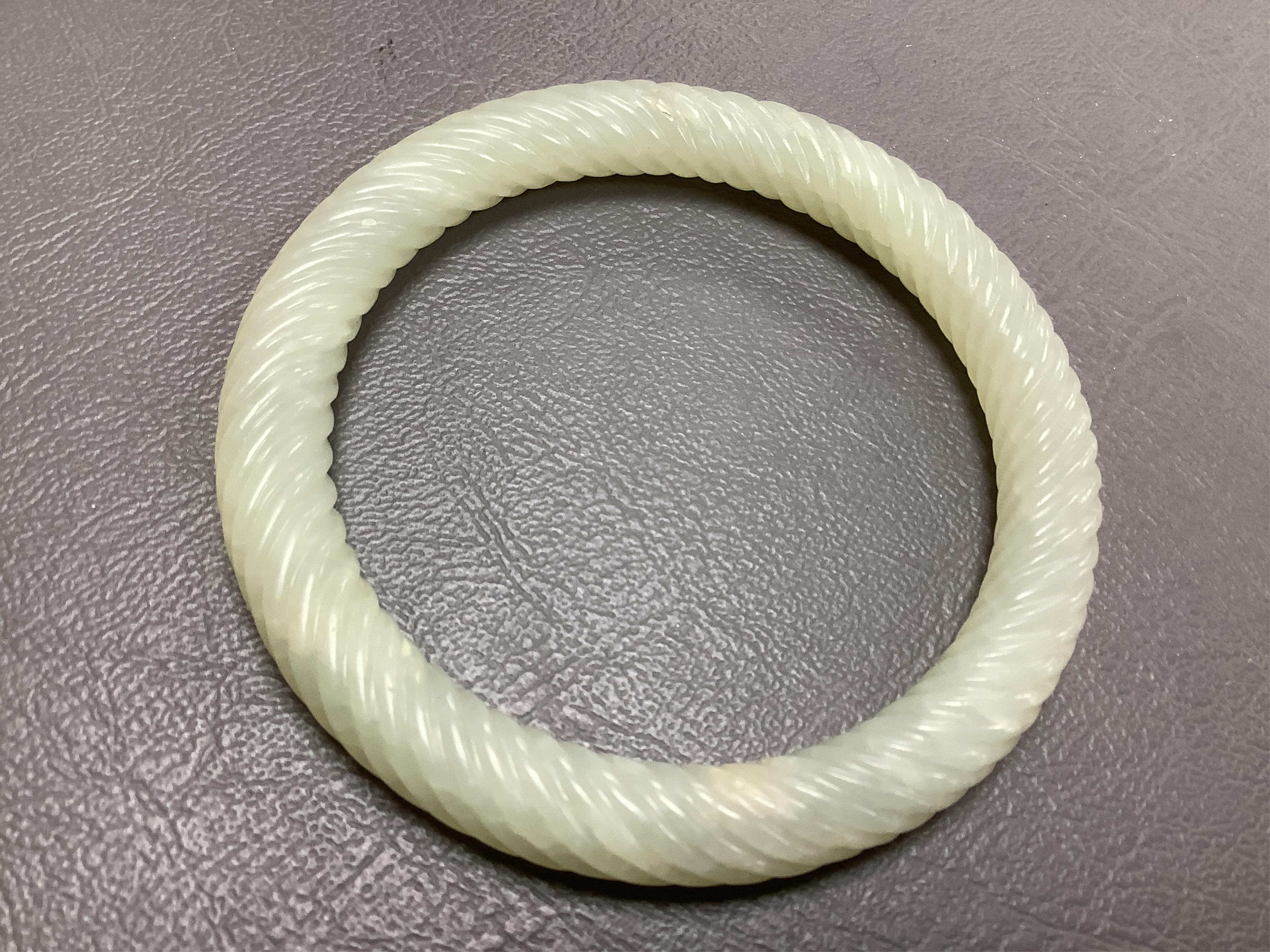 A Chinese pale celadon jade rope twist carved bangle, 8cm diameter